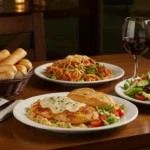 Olive Garden dinner table with Chicken Alfredo, Tour of Italy, salad, breadsticks, and wine.